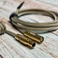 Closeup of gold FEMO 1B connector, both male and female, with a bundled mechanical keyboard cable using Teleios Fusion Black and Gold sleeving, TechFlex clear second layer, and USB connector with black heat-shrink tubing out of focus. 