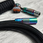 Closeup of rainbow FEMO connector and coiled mechanical keyboard cable with Teleios black sleeving and black TechFlex second layer